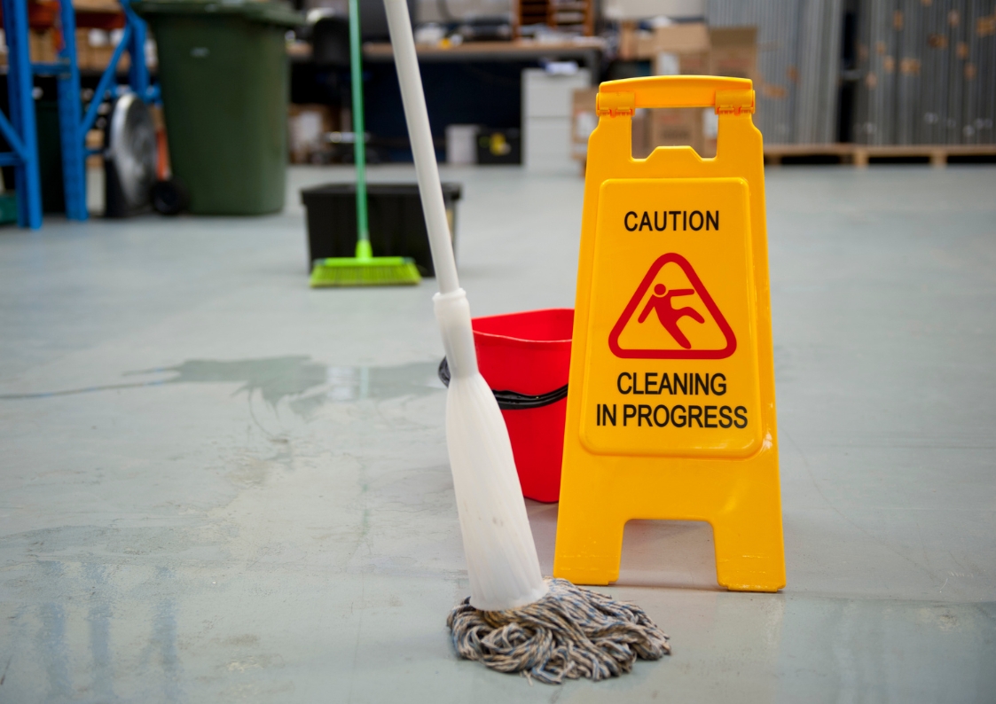 Mop oraz wiaderko stojące na podłodze na hali magazynowej.