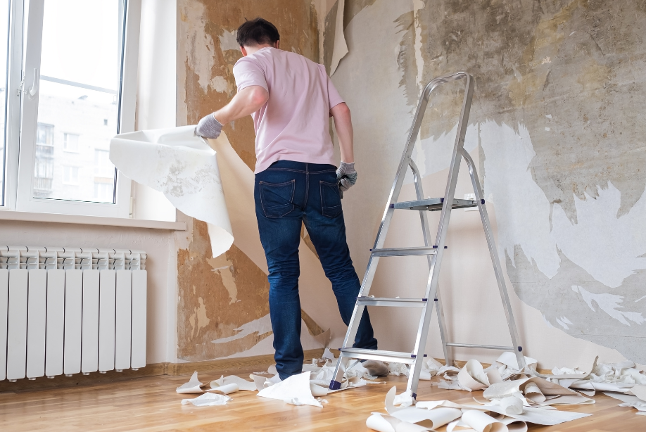 Mężczyzna zrywający tapetę ze ściany