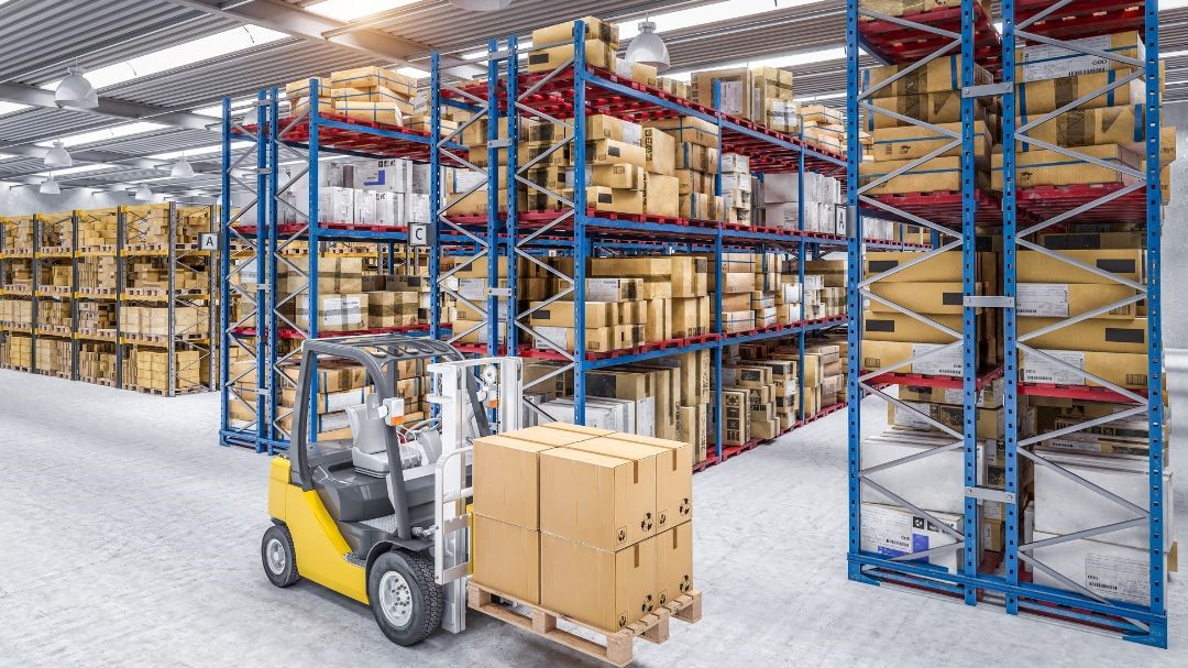 Widok magazynu z regałami pełnymi towarów oraz wózkiem widłowym, co ilustruje odpowiednie warunki przechowywania w magazynie.