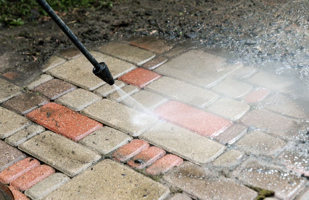 Czyszczenie kostki brukowej myjką ciśnieniową — usuwanie zabrudzeń z kolorowej kostki brukowej za pomocą strumienia wody pod ciśnieniem.